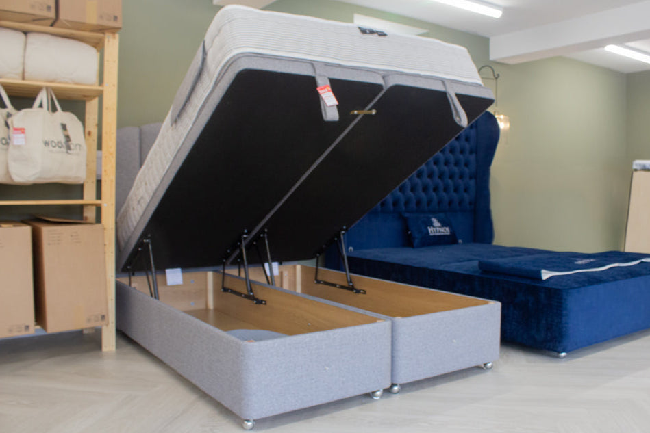 Gray upholstered Hypnos bed with storage compartment in a showroom setting