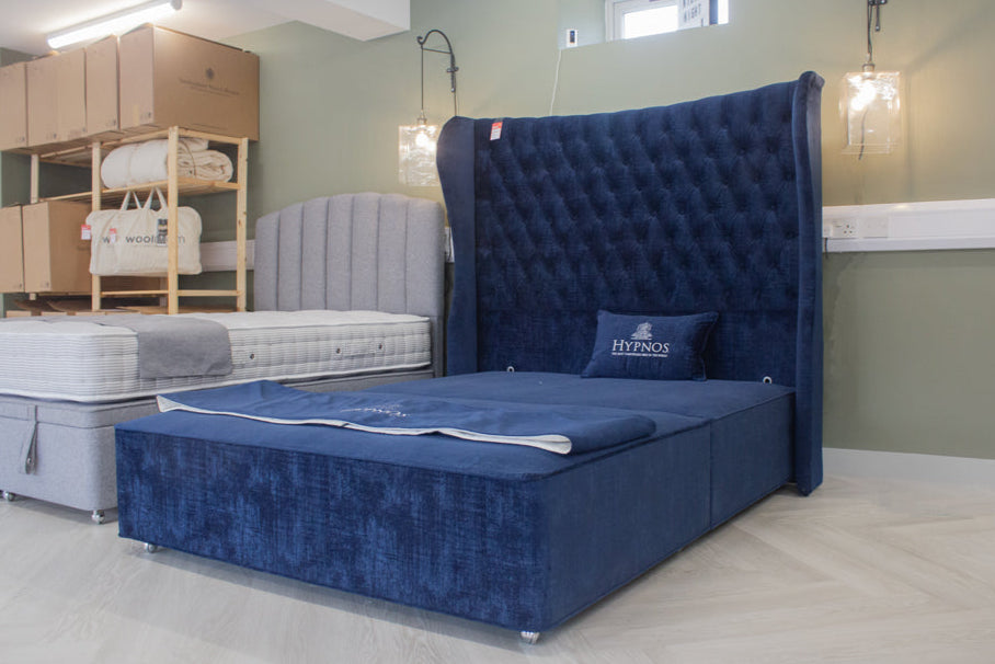 Blue upholstered bed with tufted headboard in a showroom setting