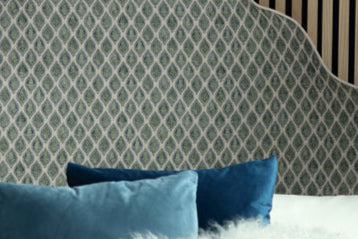 Bedroom with a patterned headboard, nightstand, and decorative pillows.