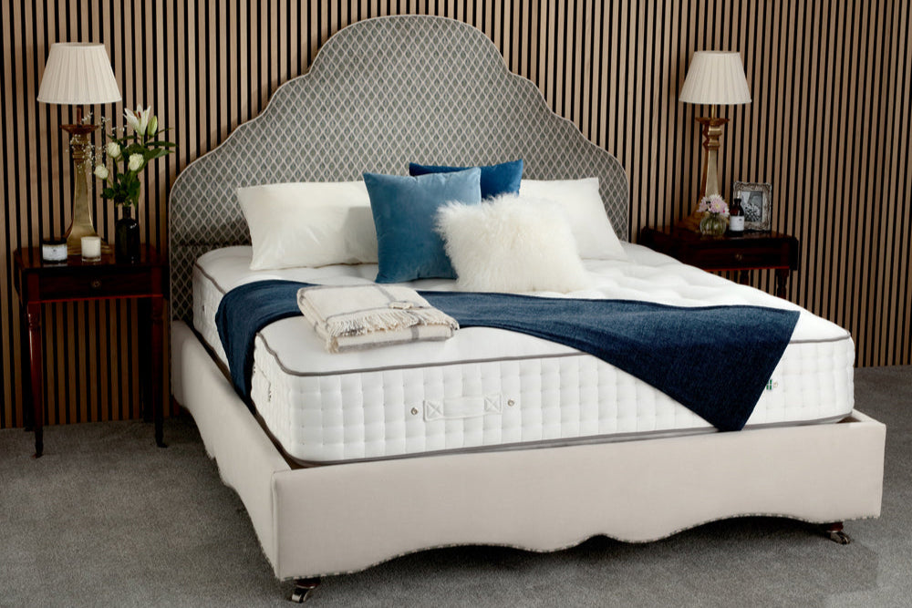 Bed with decorative pillows and a blue throw blanket in a bedroom setting.