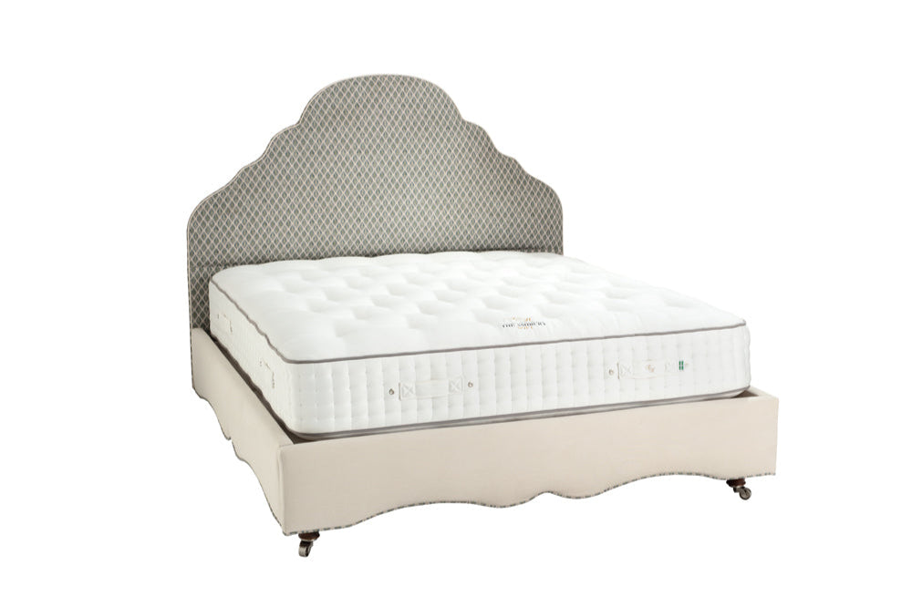 Bed with white mattress and gray upholstered headboard on a white background